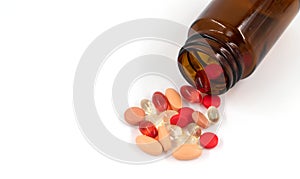 Multicolored pills and pills spilling from amber glass bottle isolated on white, medicine concept background top view