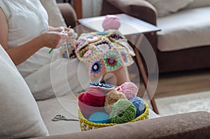 Multicolored plaid squares of crocheted on a cream colored seat and woman is crocheting