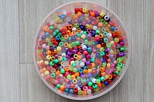 Multicolored plastic beads for handicraft are scattered on the table