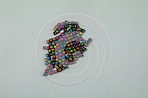 Multicolored plastic cube beads with letters scattered. background texture