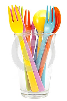 Multicolored plastic forks and spoons on glass