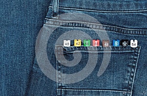 Multicolored plastic size labels on a denim backdrop