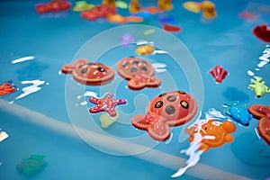 Multicolored plastic toy fish in pool for children's fishing, concept game.