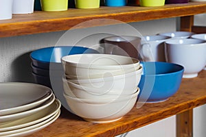 Multicolored plates and cups stand on a shelf