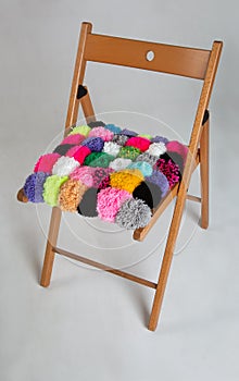 Multicolored pompons on wooden chair