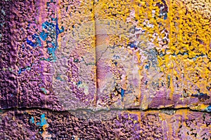 Multicolored purple orange graffiti close-up on rough concrete block wall texture