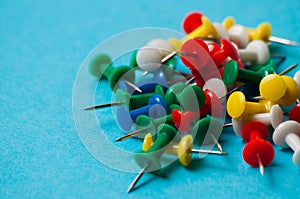 Multicolored push pins on a blue background macro closeup