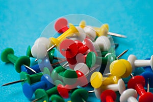 Multicolored push pins on a blue background macro closeup