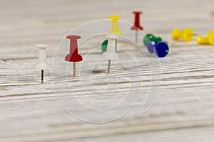 Multicolored push pins on the wooden table. Close up. Selective focus