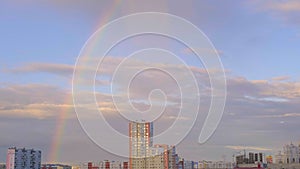 Multicolored rainbow and clouds in the sky after the rain and multi storey buildings in the city, abstraction, blurred