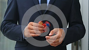 Multicolored, red-yellow-blue hand spinner, or fidgeting spinner, rotating on man`s hand. Man in a suit spinning a