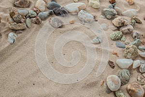 Multicolored river pebbles stones randomly lie on the sand next to the sea. Macro photography. Close-up background concept, copy