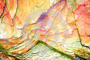 Multicolored rock wall from bottom sediments red orange dark rays crack smooth