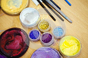 Multicolored sequins in transparent jars, and makeup brush. close up