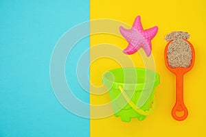 Multicolored set children`s toys for summer games in sandbox or on sandy beach on blue yellow background with copy space. Top vie