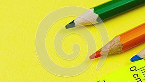 multicolored sharp wooden colored pencils lie on a pastel yellow background with a ruler