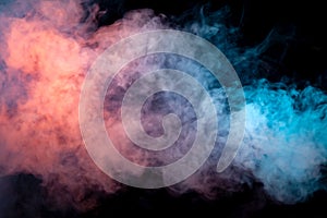Multicolored smoke from a vape of blue and purple color of the exhaled by a pillar on a black isolated background. Bright clouds