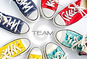 Multicolored sneakers on white background and word `TEAM` concept team work.