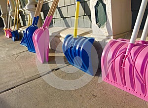 Multicolored snow shovels on sidewalk in central maine