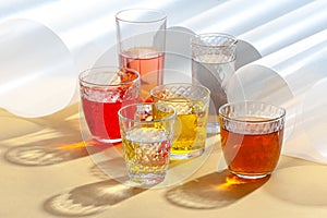 Multicolored soft drinks in glass cut glasses on a yellow table