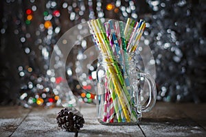 Multicolored spiral straw cocktails in a glass jar Mason on a festive New Year`s background. Sweet table. A table with a drink.