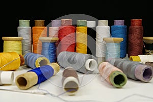Multicolored spools thread. Spools of multi-colored threads lies on white table