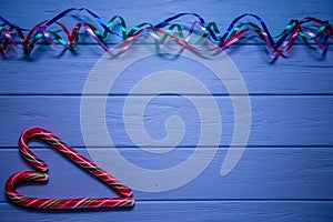 Multicolored streamer on blue wooden background with red candy with heart symbol