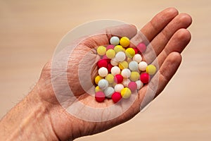 Multicolored sugar tablets in the palm. Candy in the form of balls of different colors in hand