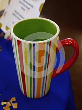 Multicolored tall stripe cup on a blue table cloth