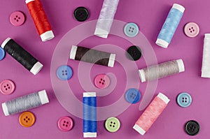 Multicolored thread spools and buttons on purple background