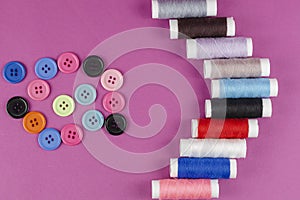 Multicolored thread spools and buttons on purple background