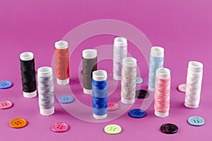 Multicolored thread spools and buttons on purple background
