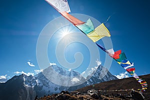 Multicolored Tibetan prayer flags with mantras flapping on the wind with High Himalayas range background. Taboche 6495m and