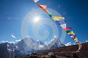 Multicolored Tibetan prayer flags with mantras flapping on the wind with High Himalayas range background. Taboche 6495m and