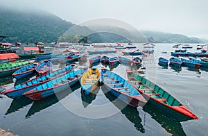 Multicolored traditional rowboats on the morning lake water in Pokhara, Gandaki Pradesh, Nepal. Asian traveling concept image