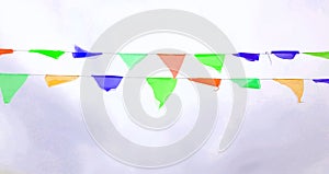 Multicolored triangular flags hang on a string and flutter in the wind against a cloudy cloudy sky