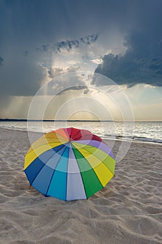 Multicolored umbrella on the beach against clouds