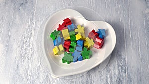 Multicolored wooden figurines toys in a white plate in the shape of a heart