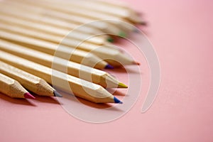 Multicolored wooden sharpened pencil rods on pink background. Drawing art tools.