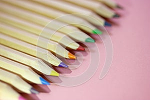 Multicolored wooden sharpened pencil rods on pink background. Tools for drawing.