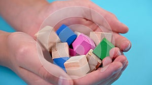 Multicolored wooden toy cubes in hands. Bright game color blocks