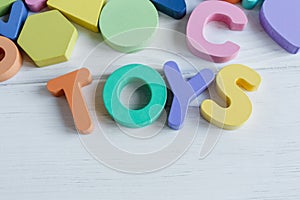 Multicolored wooden toys cubes, pyramid, letters, numbers on white wooden background. Set colorful toys for games