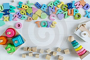 Multicolored wooden toys cubes, pyramid, letters, numbers on white wooden background. Set colorful toys for games in kindergarten