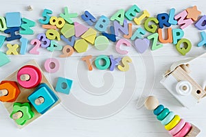 Multicolored wooden toys cubes, pyramid, letters, numbers on white wooden background. Set colorful toys for games in kindergarten