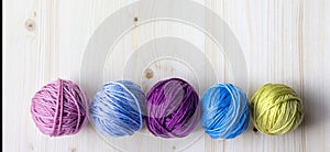 Multicolored woolen balls on wooden background. Banner.