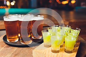 Multicolour alcoholic shots on wooden tray in nightclub.