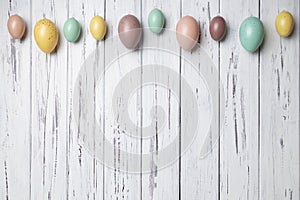 Multicoloured Easter eggs on white vintage aged wooden background. Copy space