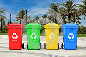 Multicoloured Garbage Trash Bins with Recycle Signs in Empty City Street with Palm Trees. 3d Rendering