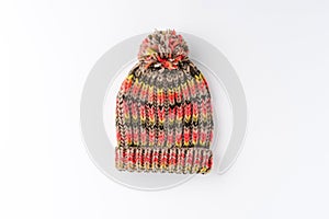 Multicoloured winter woolen hat with pompon isolated on white background. Flat lay.