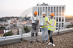 Multicultural architects with equipment working on rooftop